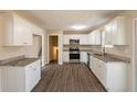 Open kitchen with white cabinets, stainless steel appliances, granite countertops, and wood-look flooring at 4547 Doral Sw Dr, Atlanta, GA 30331
