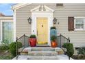Inviting entrance with a bright yellow door, decorative planters, and classic black sconces at 3495 Habersham Nw Rd, Atlanta, GA 30305