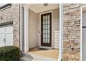 Townhome's front entrance with a brown door and stone accents at 1000 Belfry Ter, Fairburn, GA 30213