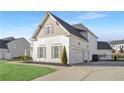 Three-car garage with white siding and a spacious driveway at 6850 Canyon Creek Way, Cumming, GA 30028