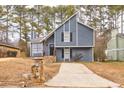 Gray house with stone accents and a paved driveway, nestled among trees at 6300 Creekford Dr, Lithonia, GA 30058