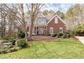 Gorgeous two-story home with brick and stucco exterior, manicured front lawn, and mature trees, creating a picturesque curb appeal at 8240 Knollbrook Ln, Mcdonough, GA 30253