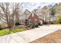 Lovely home featuring a well-manicured lawn, mature trees, long driveway, and a combination of brick and stucco architecture at 8240 Knollbrook Ln, Mcdonough, GA 30253