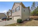 Side view of a townhome with a two-car garage, manicured lawn, and mature trees at 2166 Waterford Park Dr, Lawrenceville, GA 30044