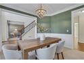 A stylish dining room features green walls, white wainscoting, and a wooden table with seating for six at 1215 Wynridge Xing, Alpharetta, GA 30005