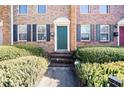 Brick townhome entry featuring a green door, black shutters, and neatly trimmed greenery at 245 Winding River Dr # E, Atlanta, GA 30350