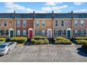 Brick townhomes with colorful doors and maintained landscaping with a parking area in front at 245 Winding River Dr # E, Atlanta, GA 30350