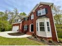 Two-story brick home with attached garage, bay window and landscaped yard at 1240 Falls Creek Ct, Conyers, GA 30094