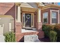 Inviting front porch featuring brick columns, a dark wooden door with wreath, and manicured shrubs at 1565 Horseshoe Creek Ln, Cumming, GA 30041