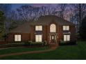 Exterior of brick home with dark shutters and inviting front entrance illuminated at dusk and green lawn at 3611 Howell Wood Trl, Duluth, GA 30096