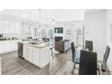 Open-concept kitchen with granite island, stainless steel appliances, and luxury vinyl flooring at 11571 Chatham Dr, Hampton, GA 30228