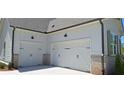 Two-car garage with carriage doors and brick base, with painted siding and black exterior lights at 4515 Aiden Way, Cumming, GA 30041