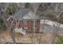 Aerial view of a brick home with green shutters, a front porch, mature trees, and a driveway at 1012 Crown River Pkwy, Mcdonough, GA 30252