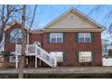 Inviting brick home with a staircase leading to the front door and green shutters against a blue sky at 1012 Crown River Pkwy, Mcdonough, GA 30252