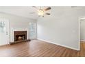 Spacious living room featuring a warm fireplace, wood floors, and ample natural light from the windows at 1012 Crown River Pkwy, Mcdonough, GA 30252