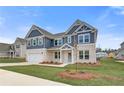 New construction home with a two-car garage, stone veneer, navy siding, and professional landscaping at 203 Arabella Pkwy, Locust Grove, GA 30248