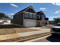 Two-story home with gray siding, brick accents, and a side view of the garage at 203 Arabella Pkwy, Locust Grove, GA 30248