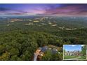 Scenic aerial view of the estate nestled within a lush, green forest with city lights in the background at 101 Barker Rd, Cumming, GA 30040