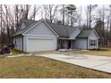 Gray house with a gray roof, white garage door, and a long driveway at 25 Water Oak Trl, Covington, GA 30014