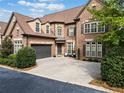 Two-story brick home with a large driveway and landscaping at 4605 Woodlawn Gates Ln, Marietta, GA 30068