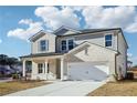 Two-story house with light brick and gray siding, a white two-car garage, and a front porch at 1569 High Falls Ln, Grayson, GA 30017