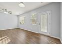 Bright living room featuring wood floors, ceiling fan, and large windows with a glass door at 2056 Wildflower Way, Conyers, GA 30012