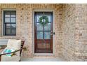 Close-up of a stylish front door adorned with a wreath, set against a backdrop of brick and a cozy porch at 3000 Smyrna Grove Dr, Smyrna, GA 30082