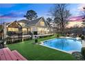 Backyard with a sparkling blue pool, green grass, mature trees, and a black iron fence at 3051 Maple Ln, Alpharetta, GA 30009