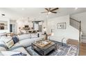Bright open-concept living room with hardwood floors and a stylish area rug next to the kitchen and stairs at 5270 Birch Valley Rd, Cumming, GA 30028