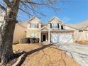 Two-story house with stone and beige accents, a two-car garage, and a tree in front at 585 Briarhurst Ct, Lawrenceville, GA 30046