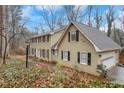 Side view of charming two-story home featuring an attached garage, a manicured lawn, and mature trees at 2225 Mountain Creek Dr, Tucker, GA 30087