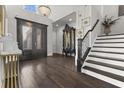 Elegant home foyer featuring a crystal chandelier, dark wood floors, glass front door, and a staircase with black accents at 1250 Atherton Park, Roswell, GA 30076