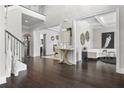 Bright foyer with dark wood floors and elegant decor, including white walls, a staircase, and a stylish console table at 1250 Atherton Park, Roswell, GA 30076