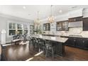 Stylish kitchen featuring dark wood cabinetry, a granite island with seating, pendant lighting, and a large window at 1250 Atherton Park, Roswell, GA 30076