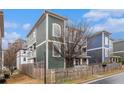 Street view showcasing the green two-story home and its neighboring blue home, framed by bare trees at 692 Rose Palm Ln, Atlanta, GA 30315