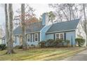 House exterior showcasing a light blue facade, neat landscaping, and a tree-lined street at 118 Knotts Landing Dr, Woodstock, GA 30188