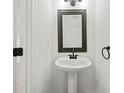 Small, clean powder room with pedestal sink and dark framed mirror at 438 Lantern Wood Dr, Scottdale, GA 30079