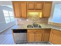 Well-lit kitchen with stainless steel dishwasher, granite countertops, and natural wood cabinets at 8504 Browns Mill Trce, Lithonia, GA 30038