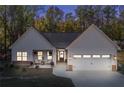 White farmhouse exterior with stone accents, two-car garage, and landscaped yard at night at 728 Harmony Rd, Temple, GA 30179