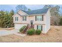 Split-level home with light siding, black shutters, a garage, landscaped bushes, and a front entrance staircase at 100 Arthurs Ln, Covington, GA 30016