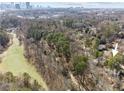 Aerial view showcasing a house nestled in a wooded neighborhood with city skyline in the distance at 1992 Walthall Nw Dr, Atlanta, GA 30318