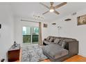 Bright living room featuring a gray sectional sofa, modern ceiling fan, and balcony access with city views at 1075 Peachtree Ne Walk # A421, Atlanta, GA 30309