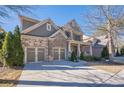 Two-story home with stone and siding accents, three-car garage, and front porch at 9994 Inisfree Dr, Johns Creek, GA 30022