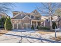 Two-story home with stone and siding accents, three-car garage, and front porch at 9994 Inisfree Dr, Johns Creek, GA 30022