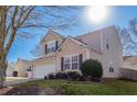 Two-story house with beige vinyl siding, a white garage door, and mature shrubs at 104 Holly Mill Village Dr, Canton, GA 30114