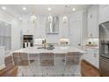 Modern white kitchen with an island, stainless steel appliances, and hardwood floors at 124 Everley Walk, Alpharetta, GA 30009