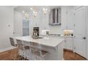 Modern kitchen features white cabinets, stainless steel appliances, an island with barstool seating, and pendant lights at 124 Everley Walk, Alpharetta, GA 30009