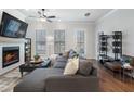 Cozy living room with fireplace, large TV, and comfortable gray sectional sofa. Hardwood floors throughout at 124 Everley Walk, Alpharetta, GA 30009