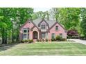 Lovely two-story brick home with mature trees, lush green lawn, and well-maintained landscaping at 5915 Masters Club Dr, Suwanee, GA 30024
