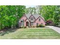 Beautiful two-story brick home featuring manicured lawn, mature trees, and a well-kept front yard at 5915 Masters Club Dr, Suwanee, GA 30024